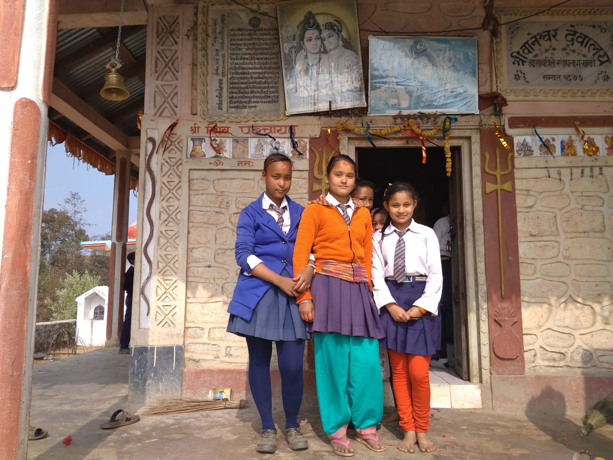 Three girls stand outside temple in school uniform.